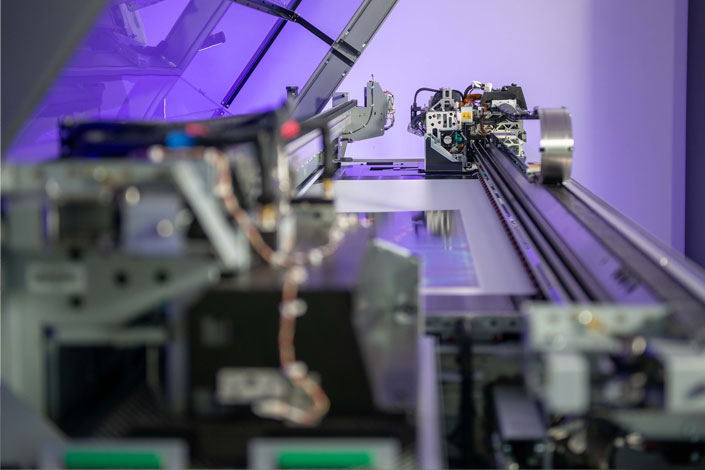 Close-up of a large-format roll-to-roll printer head applying vibrant ink to a flexible vinyl banner.