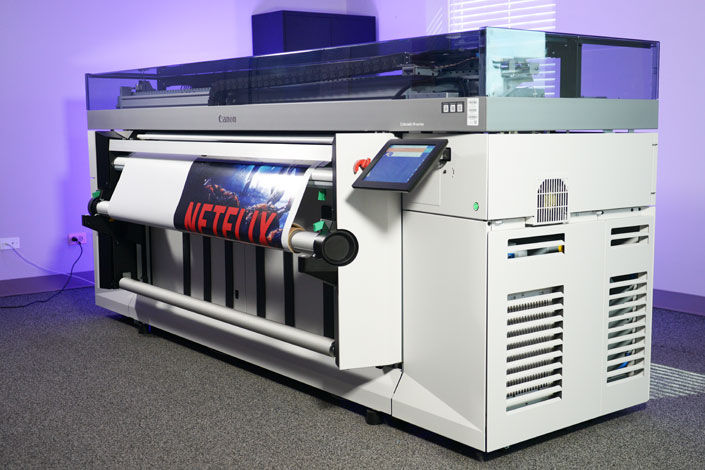 Large-format roll-to-roll printer producing a vibrant backlit graphic on flexible media.