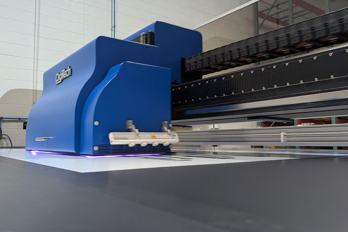Industrial Digitech UV flatbed printer producing a high-resolution graphic on a rigid substrate at Infused Color Graphics.